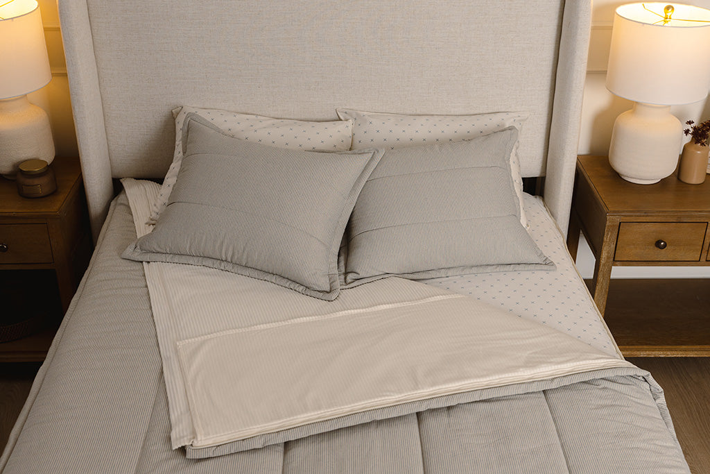 Overhead photo of blue striped zipper bedding with cream and blue crossed bed sheets and cream corduroy minky interior.