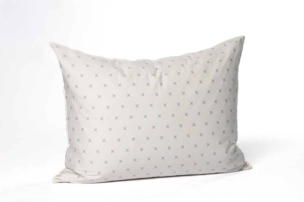 A soft white and light blue x printed pillowcase on a white backdrop.