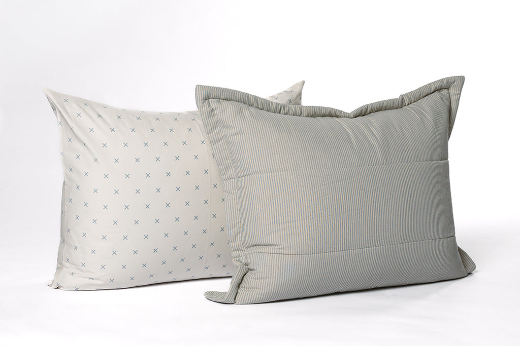 A soft white and light blue x printed pillowcase with a soft white and light blue striped sham on a white backdrop.