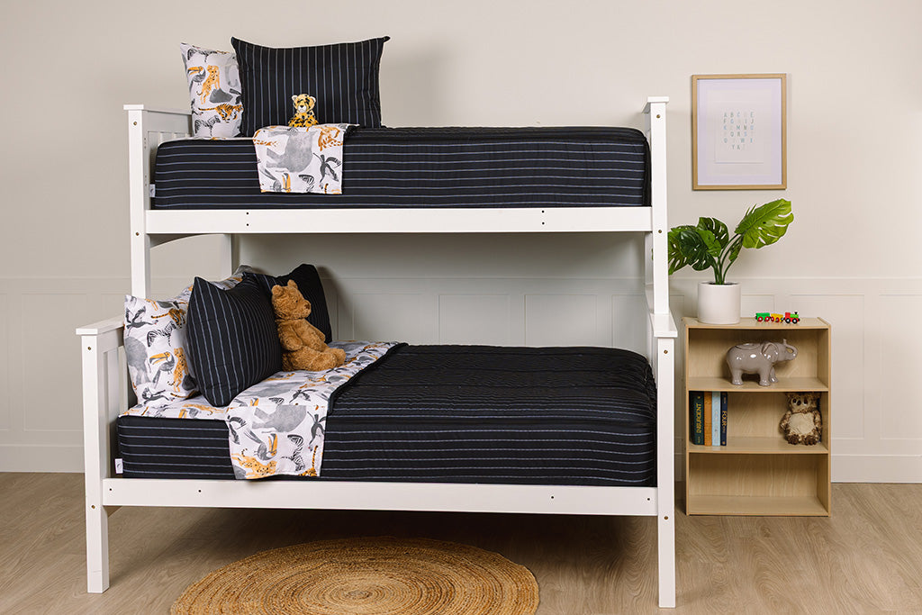 A bunk bed with the top twin and bottom full made with black and jungle printed zipper bedding and stuffed animals on each bed. 