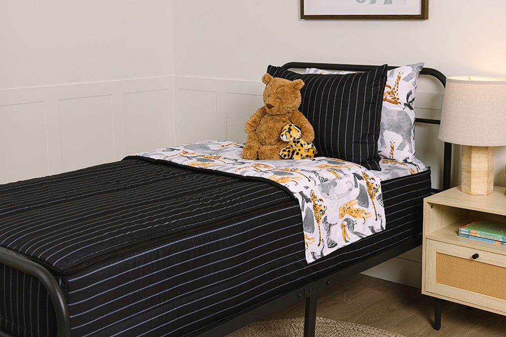 Children's zipper bedding in a bedroom on a black bed frame that has a black exterior and animal print interior, with a stuffed teddy bear and stuffed, toy cheetah. 