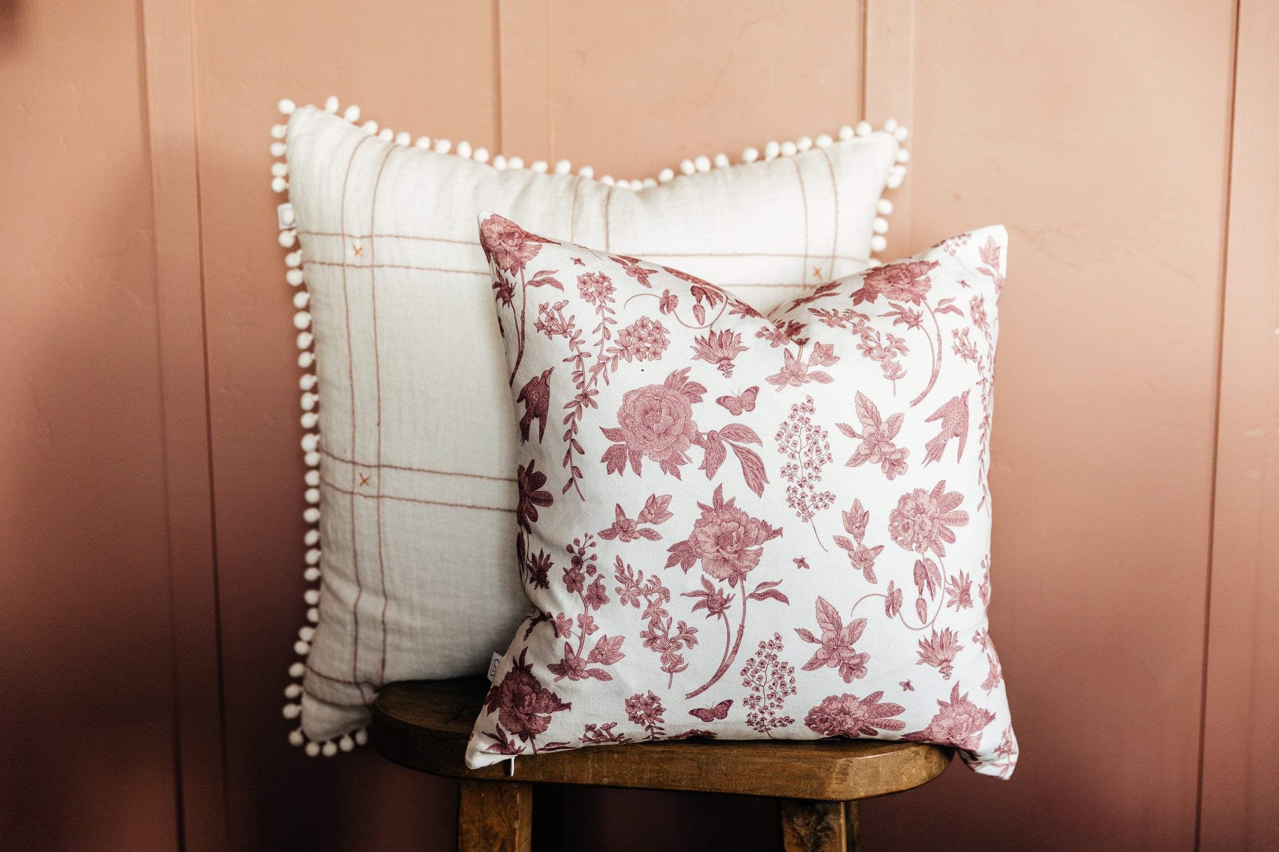 Pink floral and white pillows stacked on stool