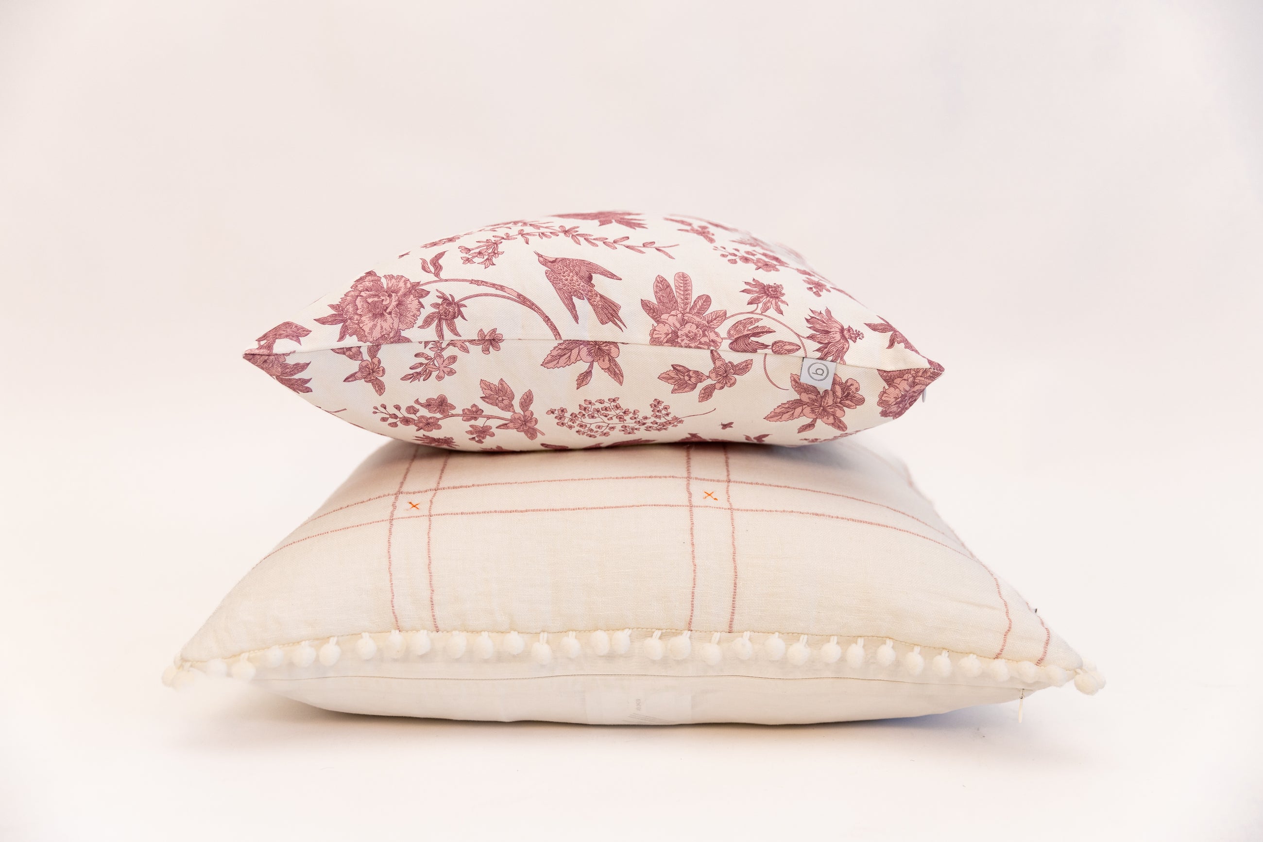 White and Pink floral pillows stacked on white background