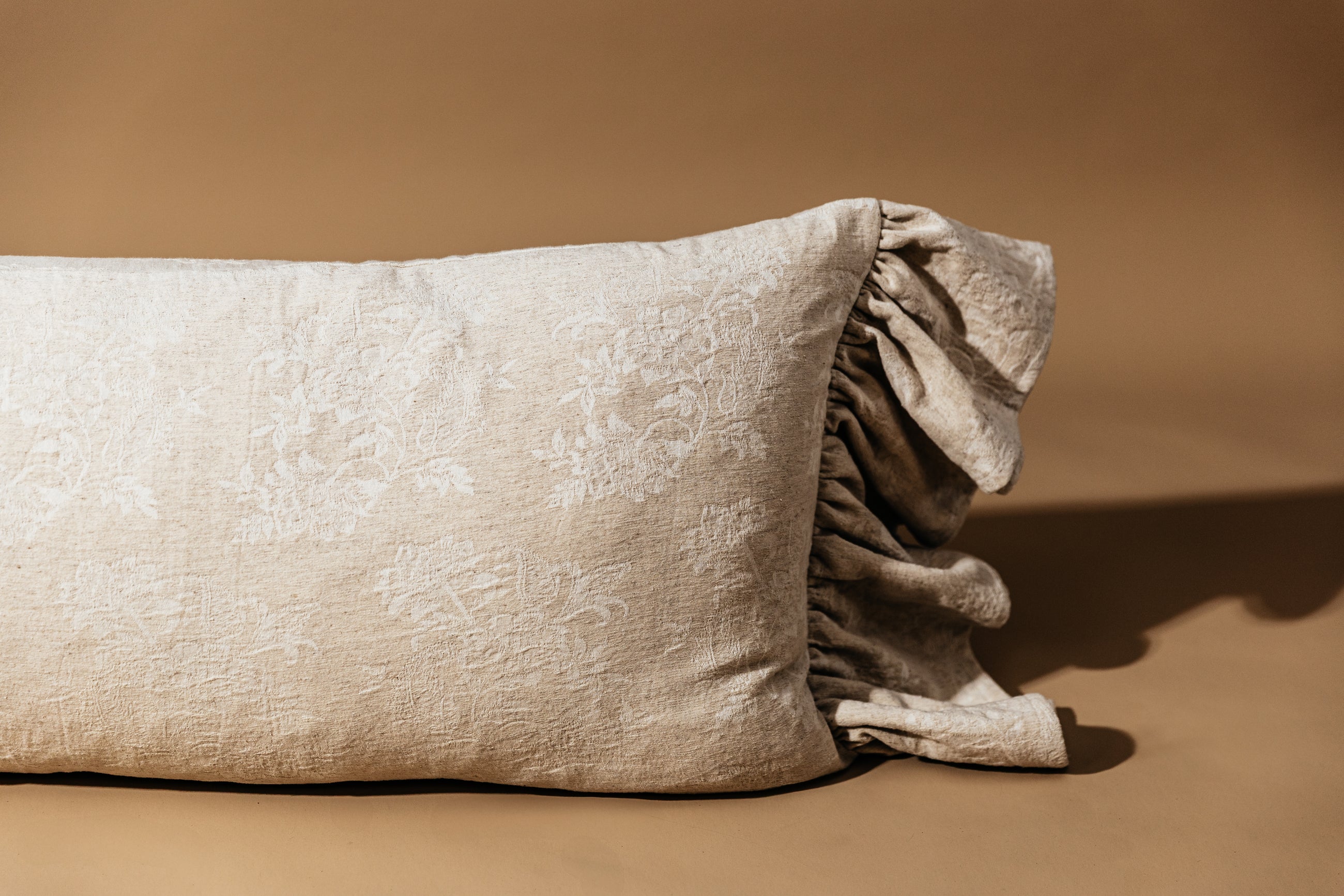 Tan floral embossed lumbar pillow on tan background