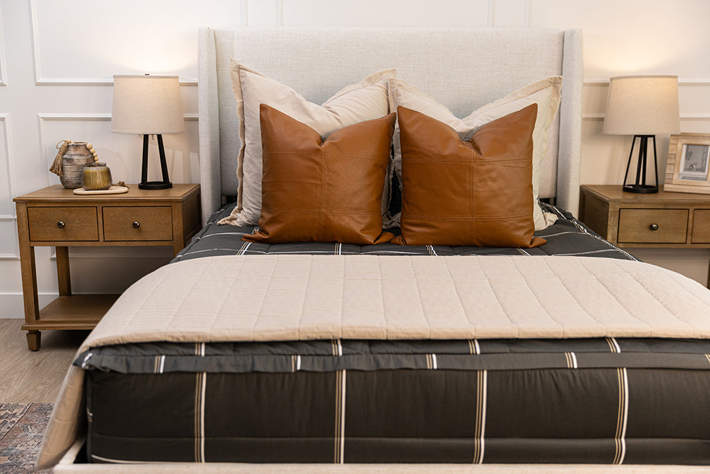 A close up of the neutral brown throw pillows on a set of black plaid zipper bedding