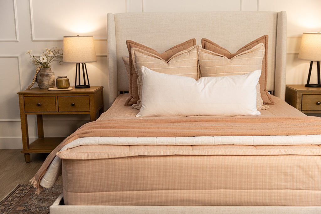 Close up shot of the terra cotta, pink, and white pillows on the bed made with peachy pink zipper bedding