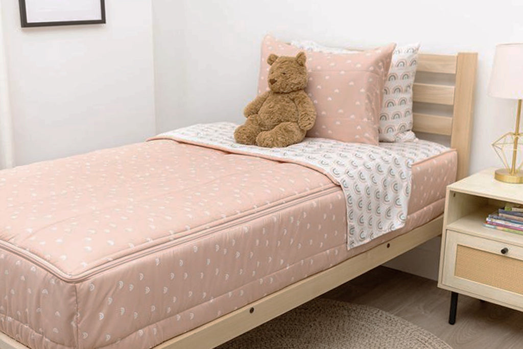 bedroom with twin bed decorated with peachy pink rainbow printed zipped bedding and toys on the ground