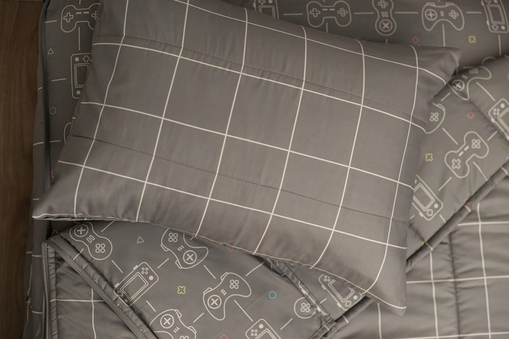 Gaming printed kids zipper bedding with the top unzipped and one side pulled back to reveal the inside lining, the pillow tossed on top of the bed.