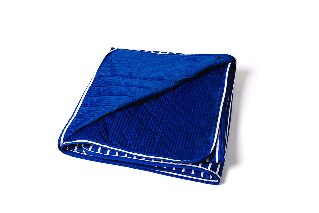 A blue and white striped blanket with a minky interior folded on a white backdrop.
