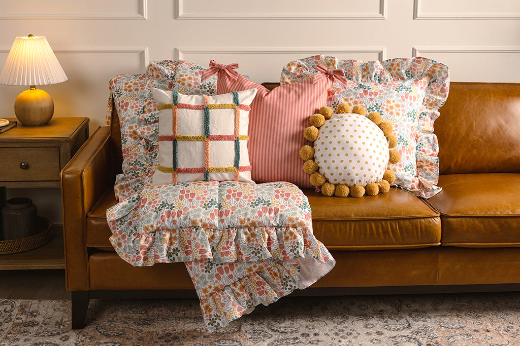 Multi-color and floral print accessories on an orange leather couch.