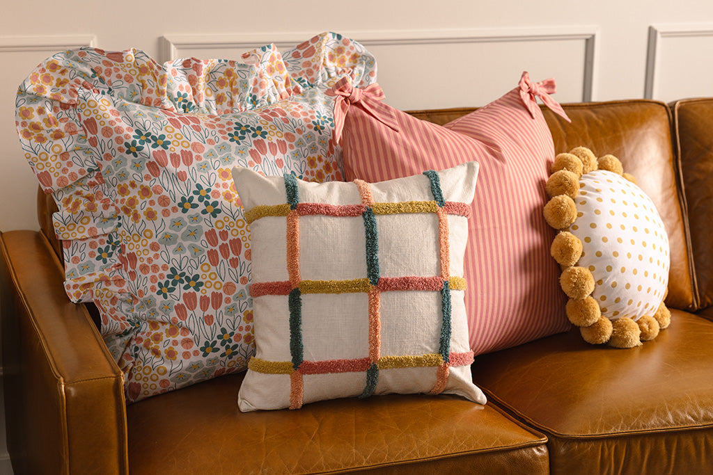 Multi-color and floral accessories on an orange leather couch.