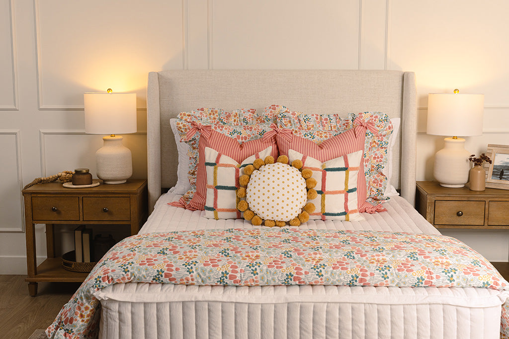 White quilted zipper bedding with multi-color and floral accessories on a queen bed.
