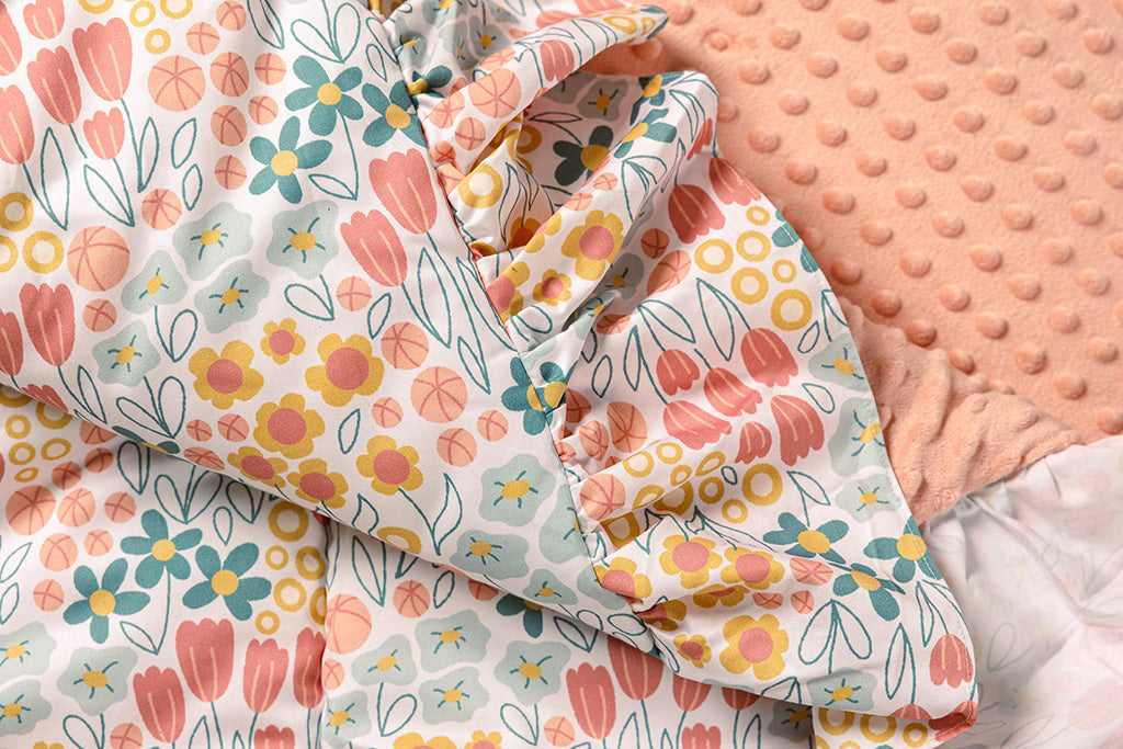 A multi-color floral print blanket with pink bubble minky.