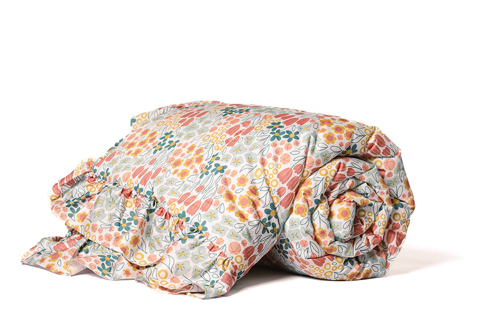 A multi-color floral blanket with pink bubble minky on a white background. 