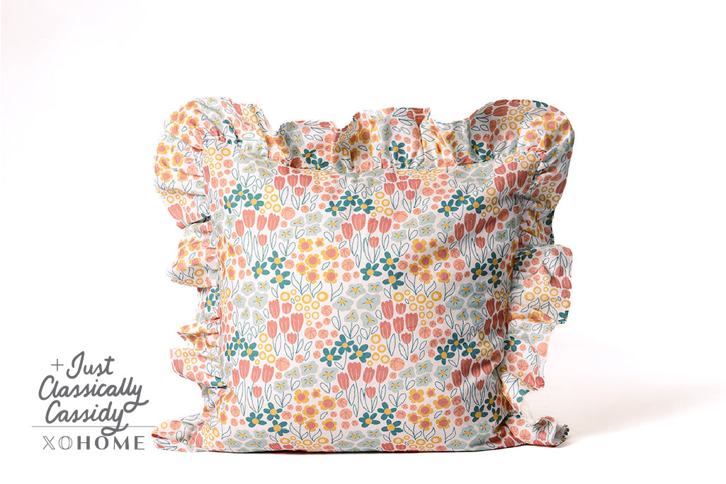 A multi-color floral pillow on a white backdrop.