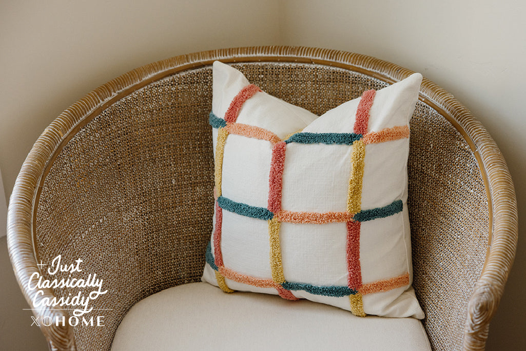 Multi-color grid pillow on a tan chair.