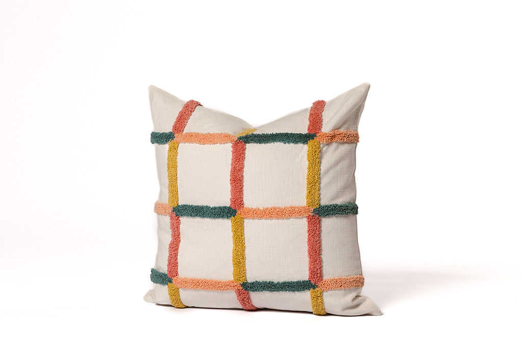 Multi-color grid pillow on a white backdrop.