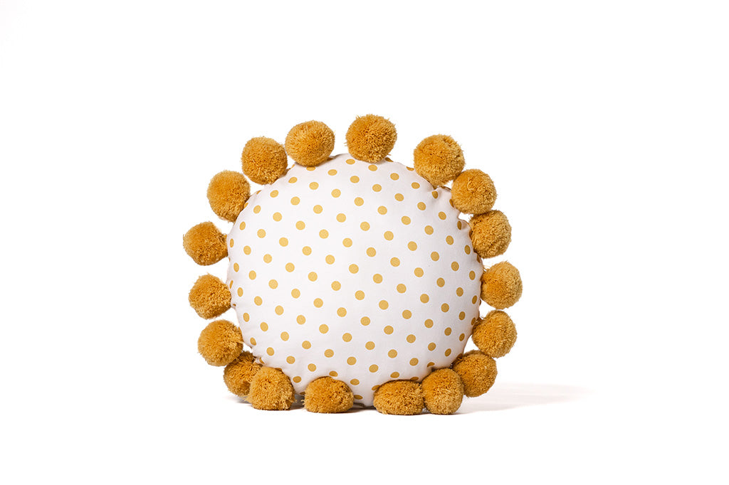 A yellow and white polkadot circular pillow on a white backdrop.