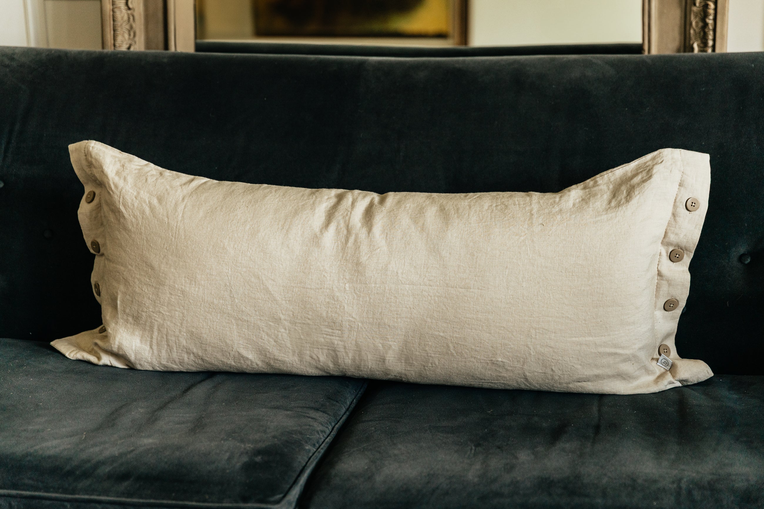 A lumbar linen pillow on a black velvet couch.