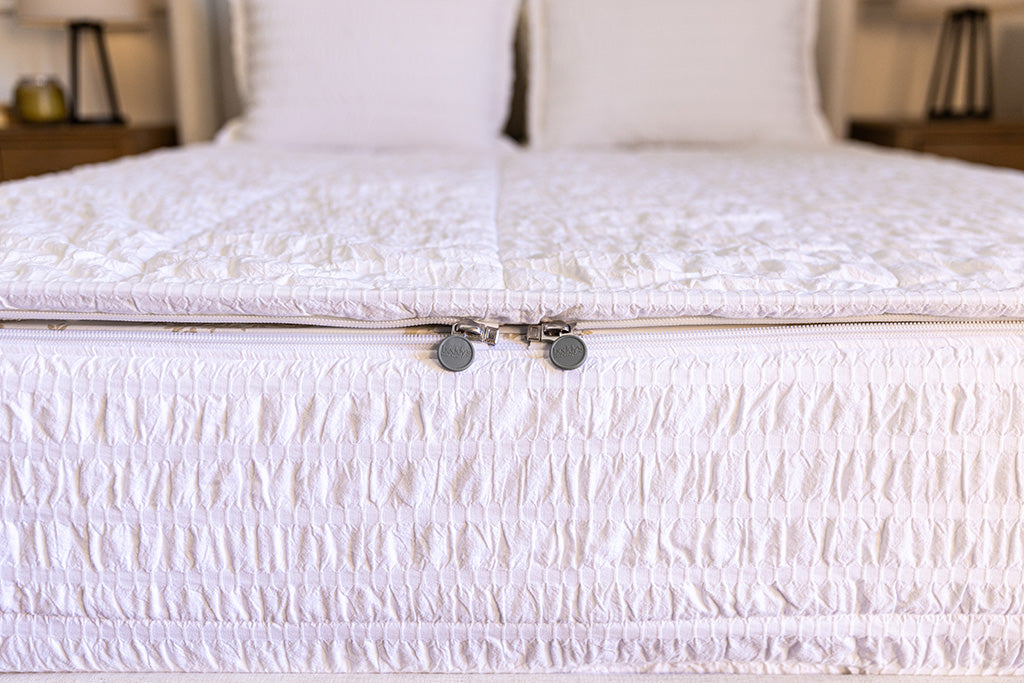 The foot of a bed made with seersucker white zipper bedding showing where the two zippers are located.