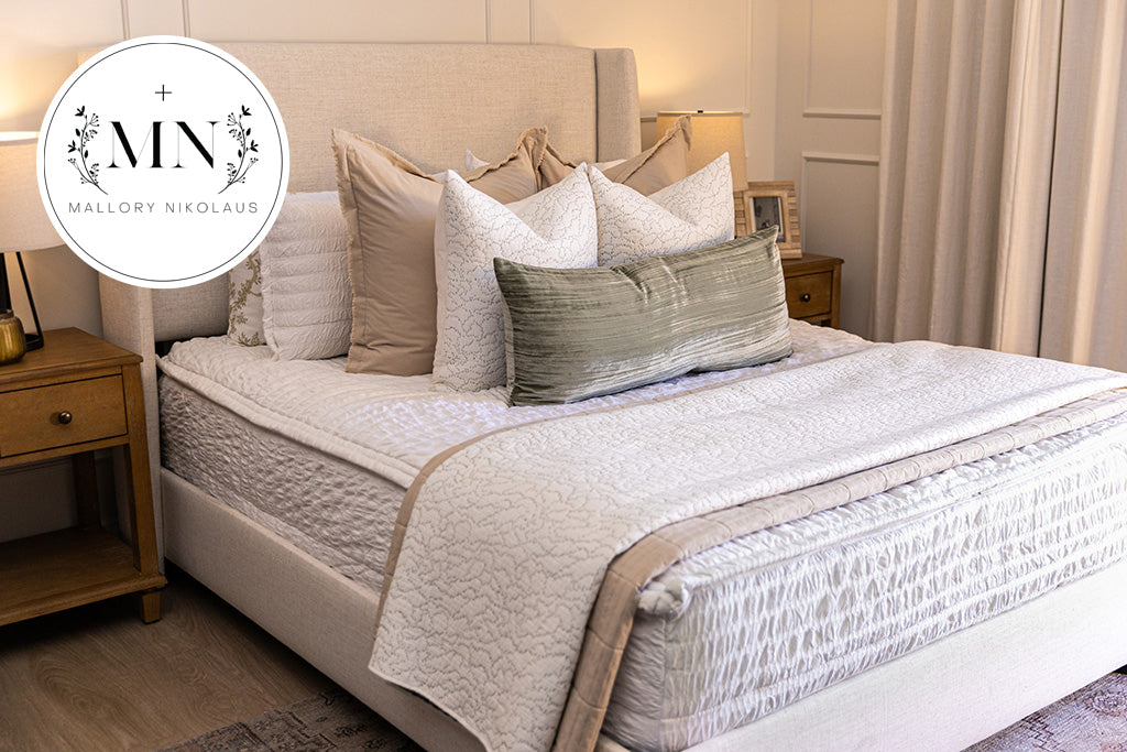 A queen bed made with white seersucker zipper bedding and an assortment of neutral bedding accessories, designed by interior designer Mallory Nkolaus