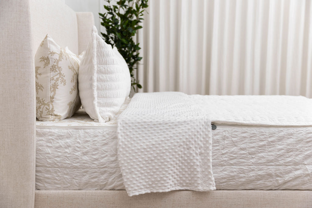Side shot of a bed made with white seersucker zipper bedding, the top pulled back to reveal the minky lining.