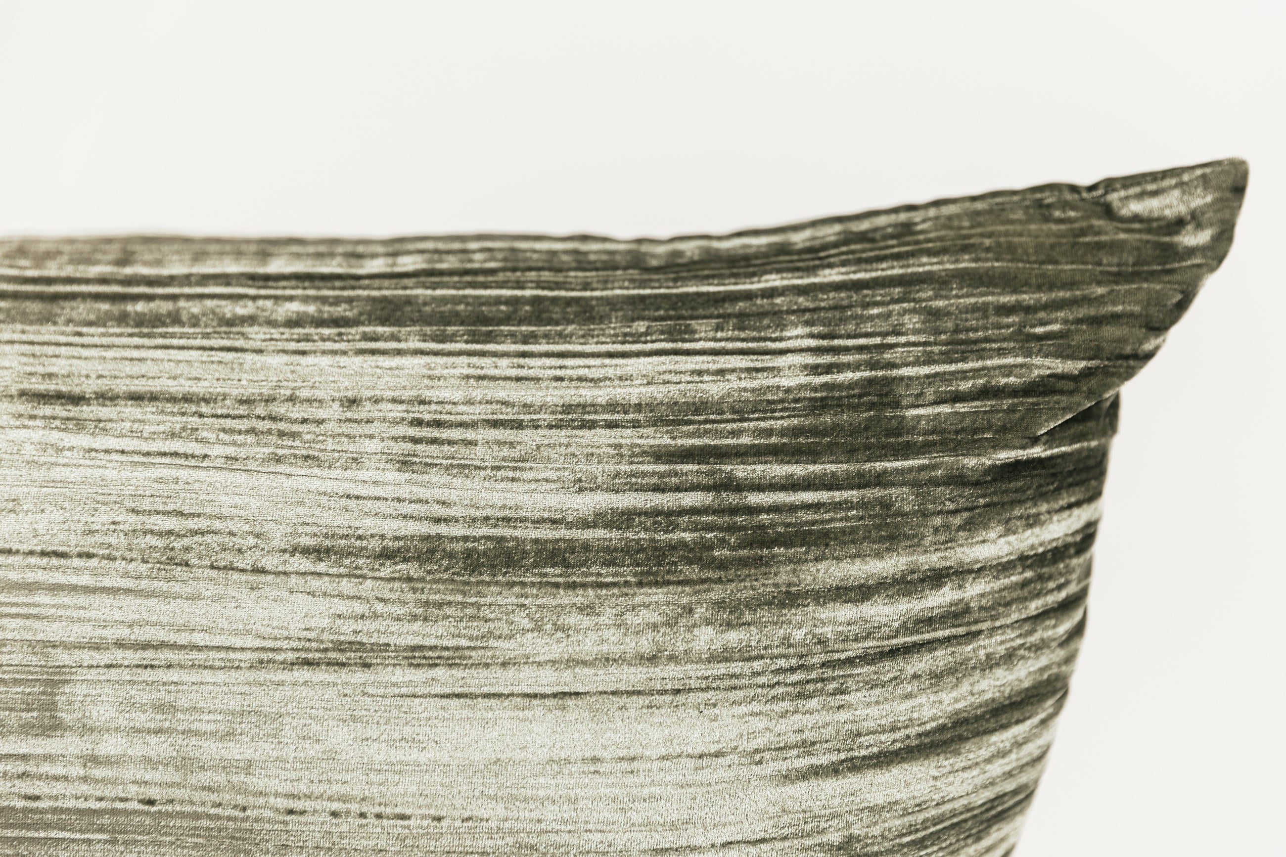 A close up corner view of a green XL velvet lumbar pillow on a white background.