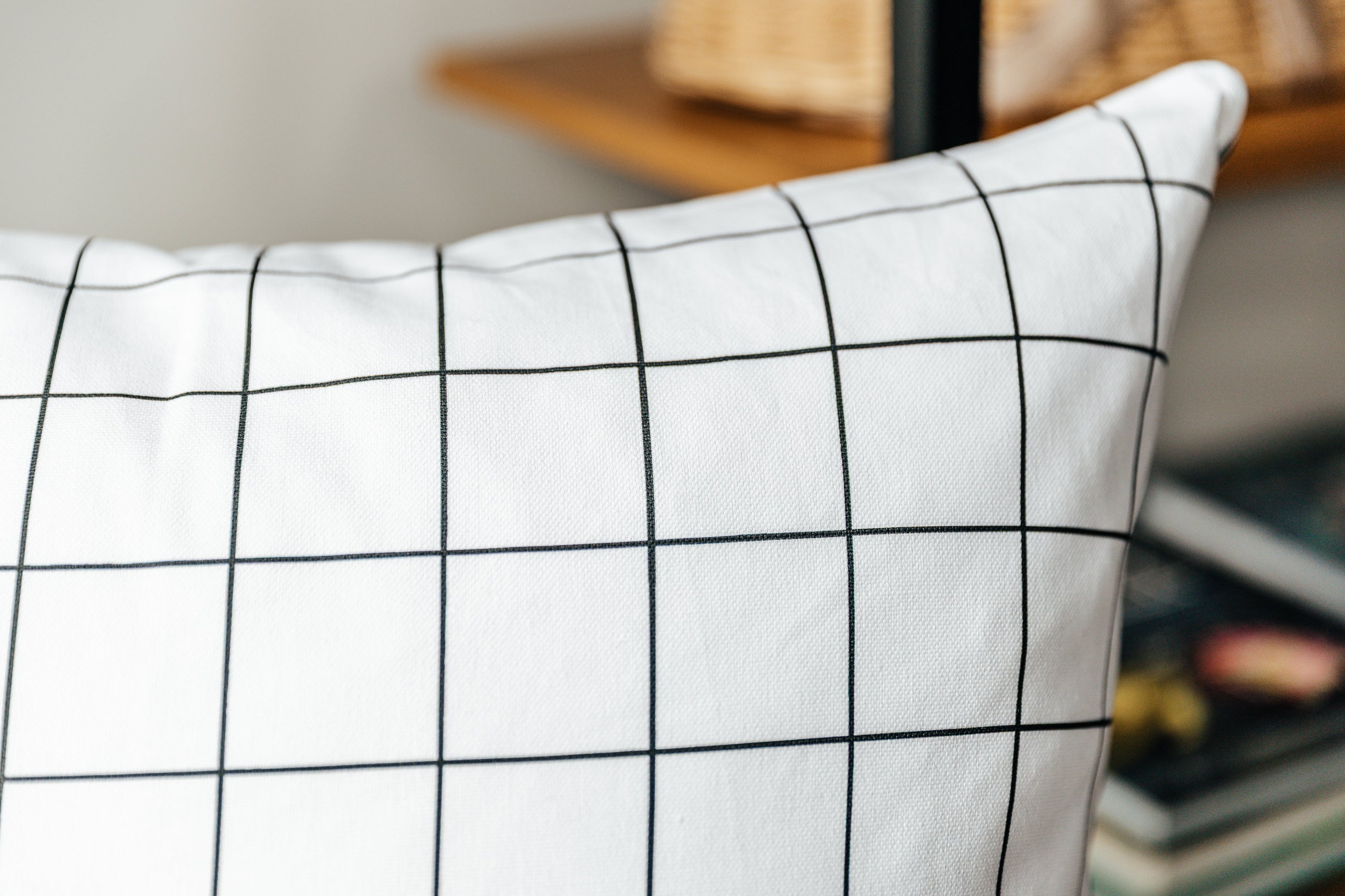 A close up corner view of a white euro pillow with a black grid pattern.