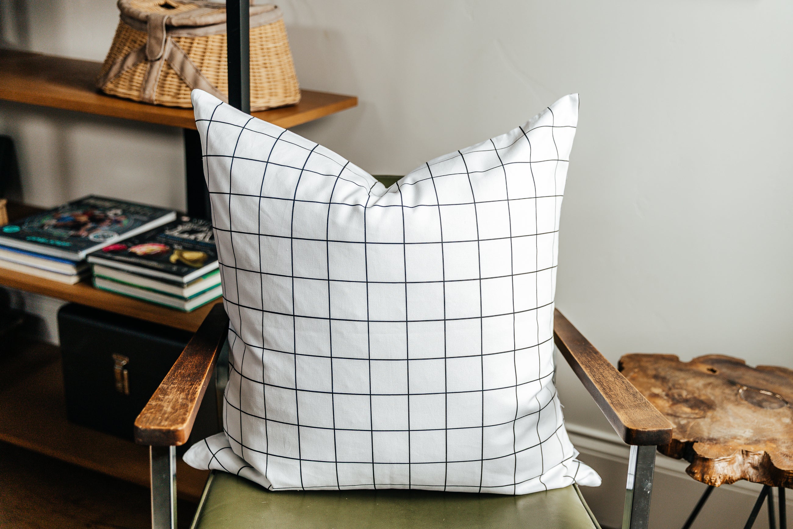 A white euro pillow with a black grid pattern arranged on a green metal chair.