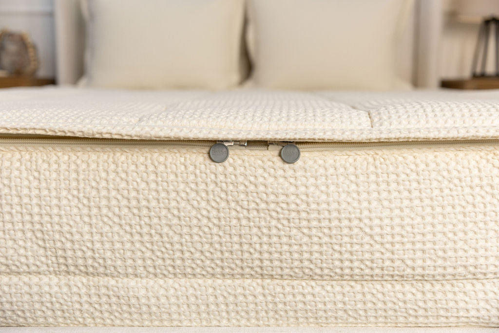 End of bed showing double zippers on cream waffled zipper bedding.