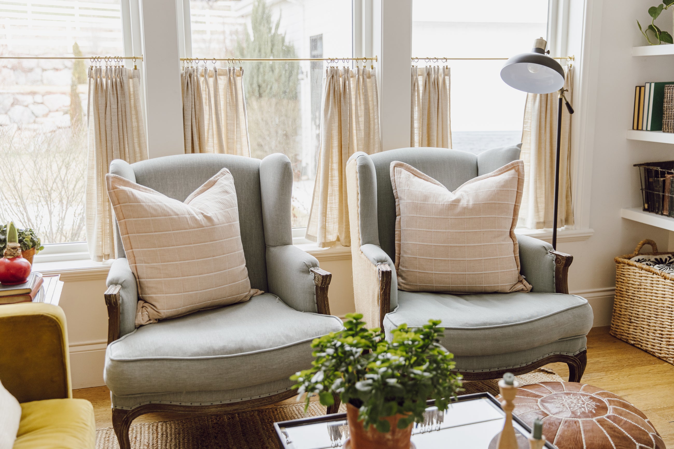 Two plaid terracotta euro pillows arranged on light blue antique chairs in a living room.