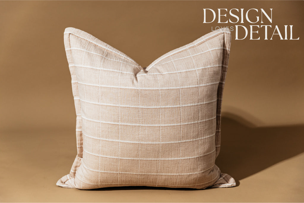 A plaid terracotta euro pillow arranged on a brown background.