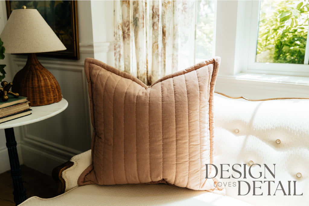 A terracotta quilted pillow on a cream antique coach. 