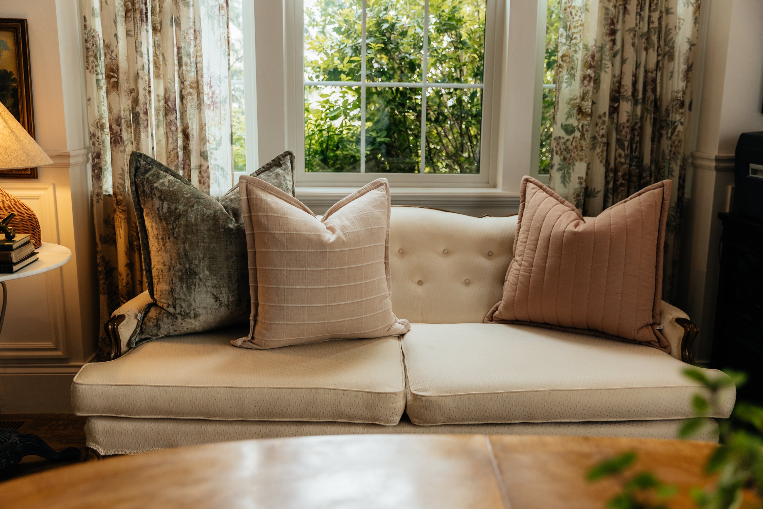 A cream antique coach with an arrangement of velvet green and terracotta matching pillows.