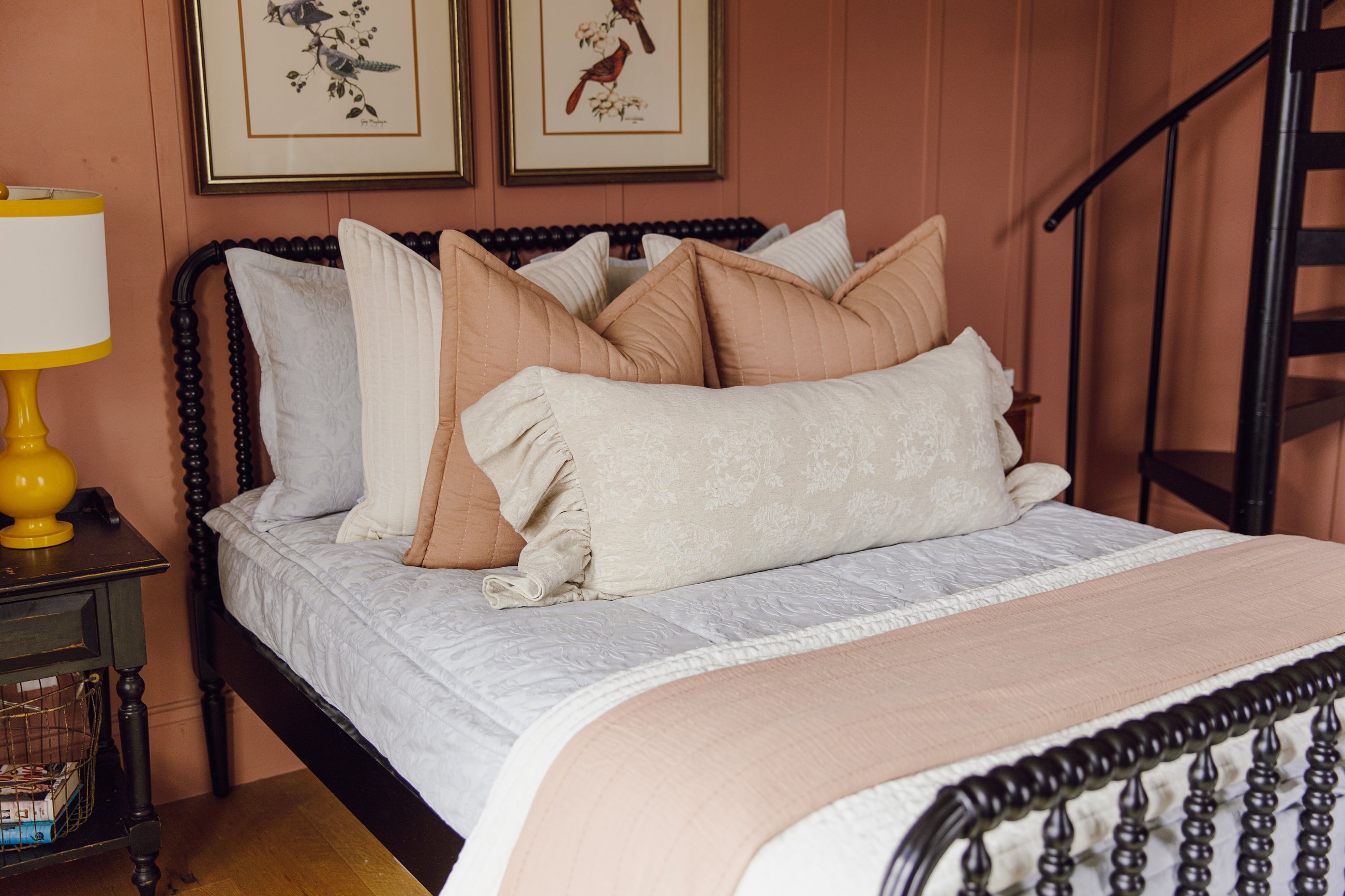A bed made with texture light blue zipper bedding and an arrangement of neutral and terracotta pillows and blankets.