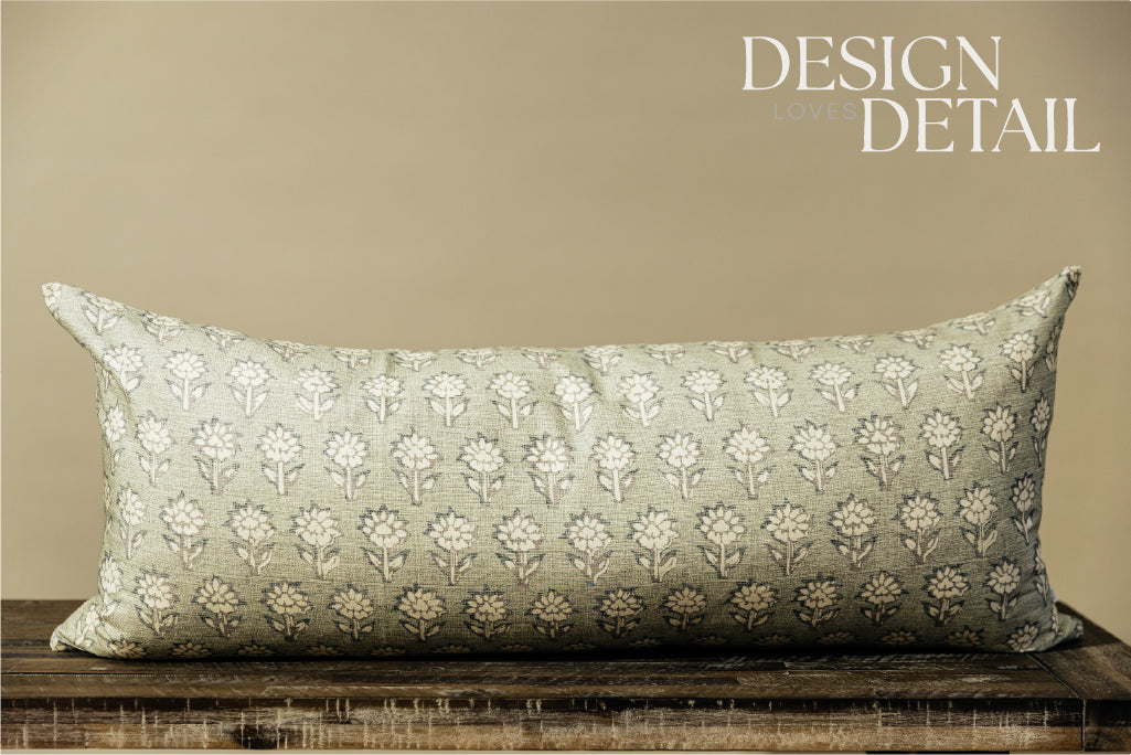 A sage green and blue floral pattern XL lumbar pillow arranged on a bench with a light green background.