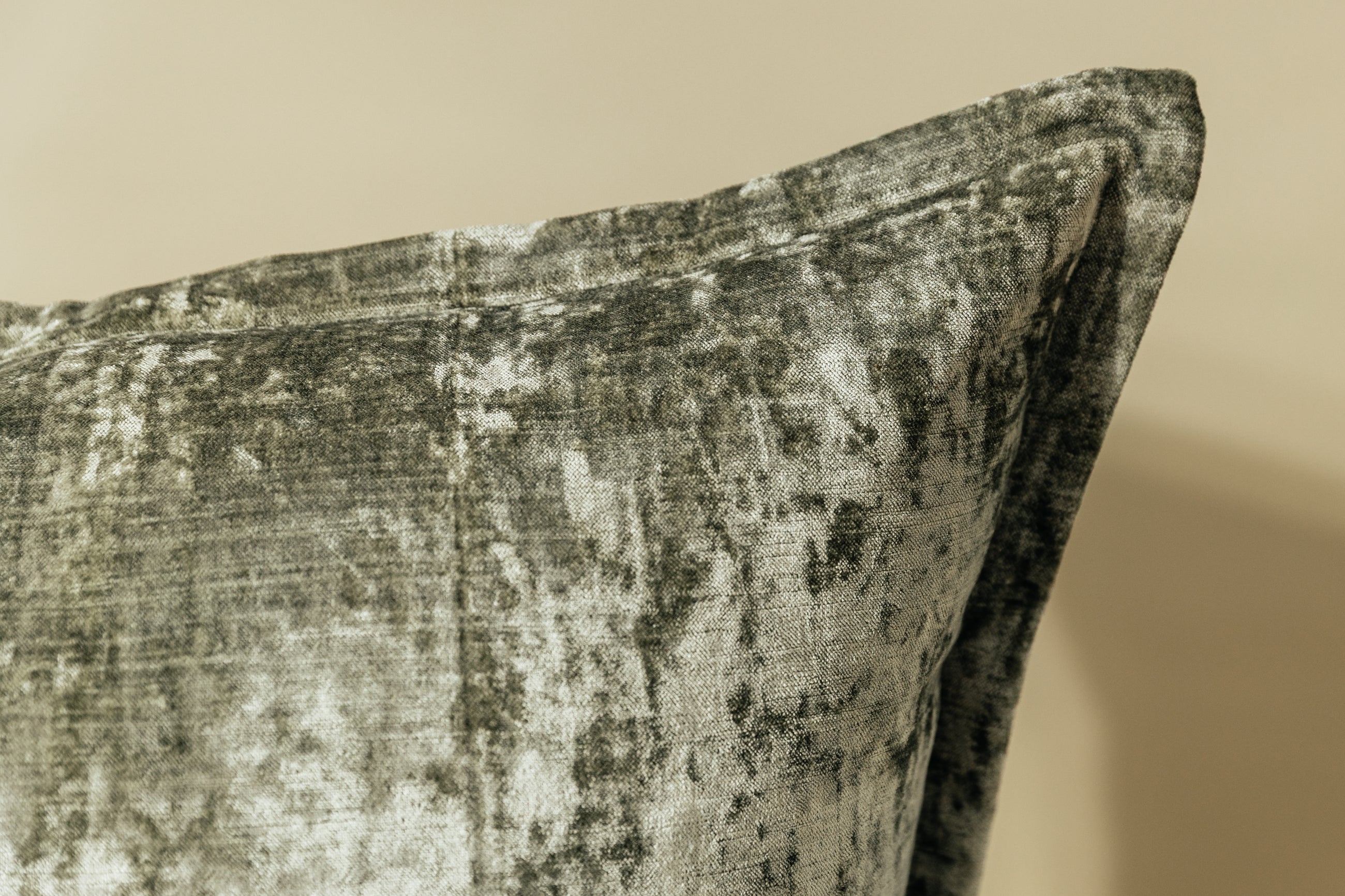 A close up corner view of a sage velvet green XL euro pillow arranged on a light green background.