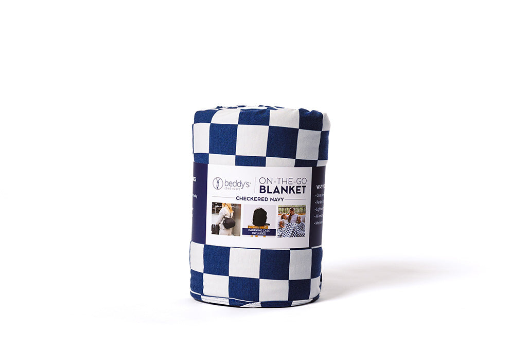 A navy and white check blanket wrapped up with a band on a white backdrop.