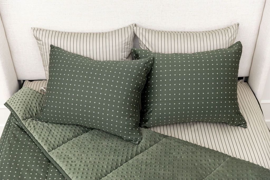 Dark green zipper bedding with small cross design unzipped showing striped interior sheet and cozy green minky