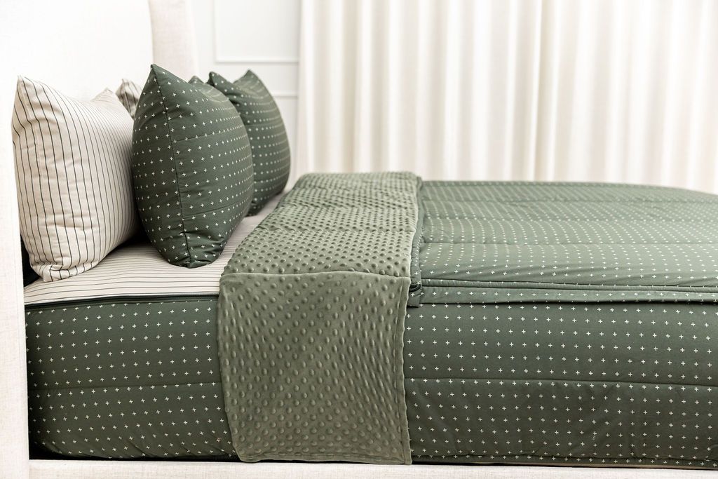 Dark green zipper bedding with small cross design unzipped showing striped interior sheet and cozy green minky
