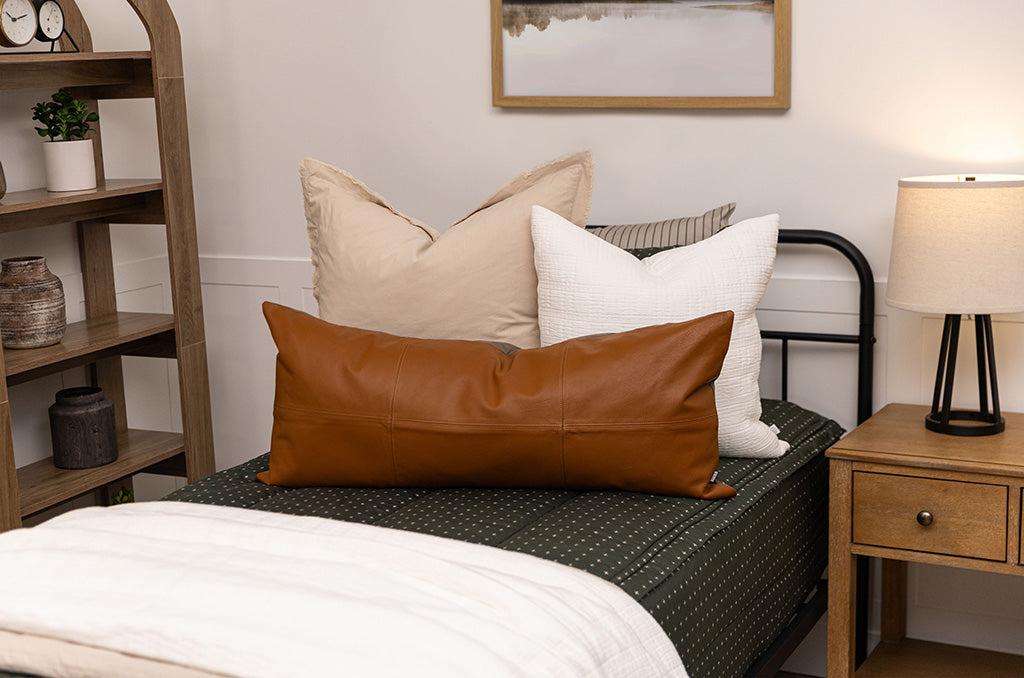 twin bed with Dark green zipper bedding with small cross design paired with tan, cream and brown pillows and blankets