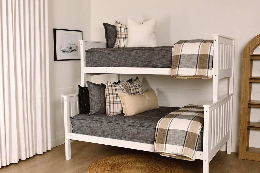 A bunk bed made with dark charcoal gray zipper bedding and leather and neutral striped pillows and blanket.