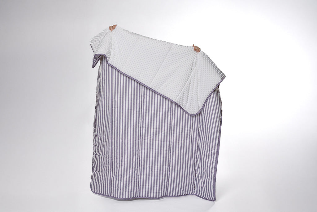 A purple and white striped blanket with white bubble minky on a white backdrop. 