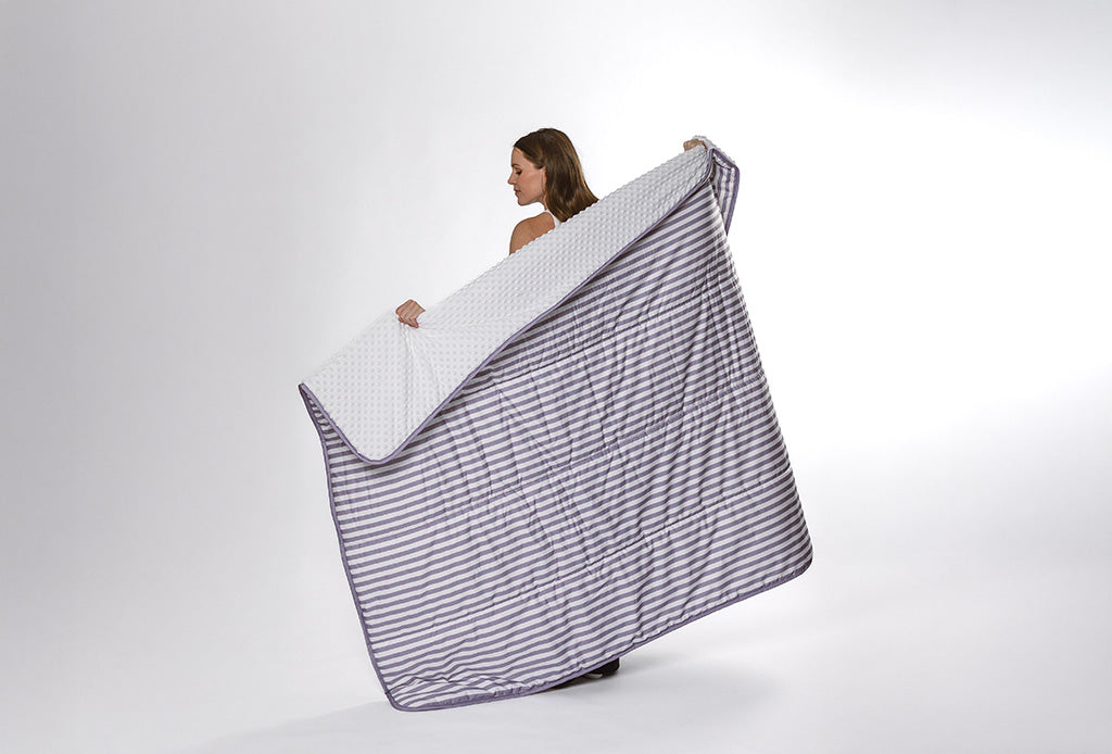 A purple and white striped blanket with white bubble minky being held by a woman on a white backdrop. 