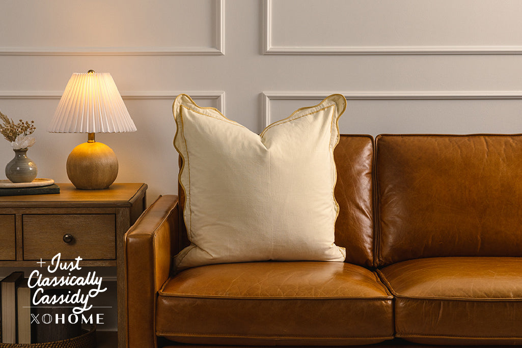 A butter cream pillow on an orange leather couch.