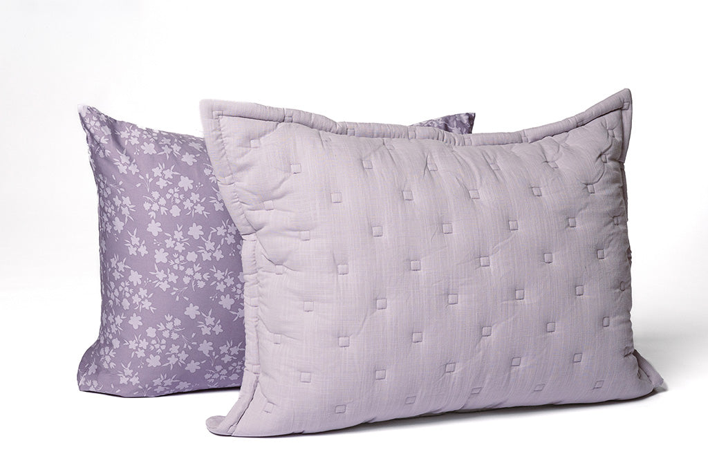 A floral purple pillowcase ad purple knitted sham on a white backdrop.