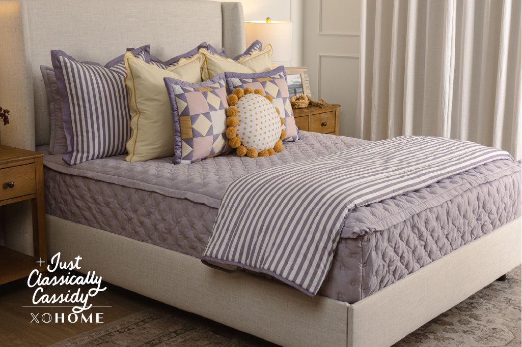 Puffed, purple zipper bedding with yellow, purple, and white accessories. 