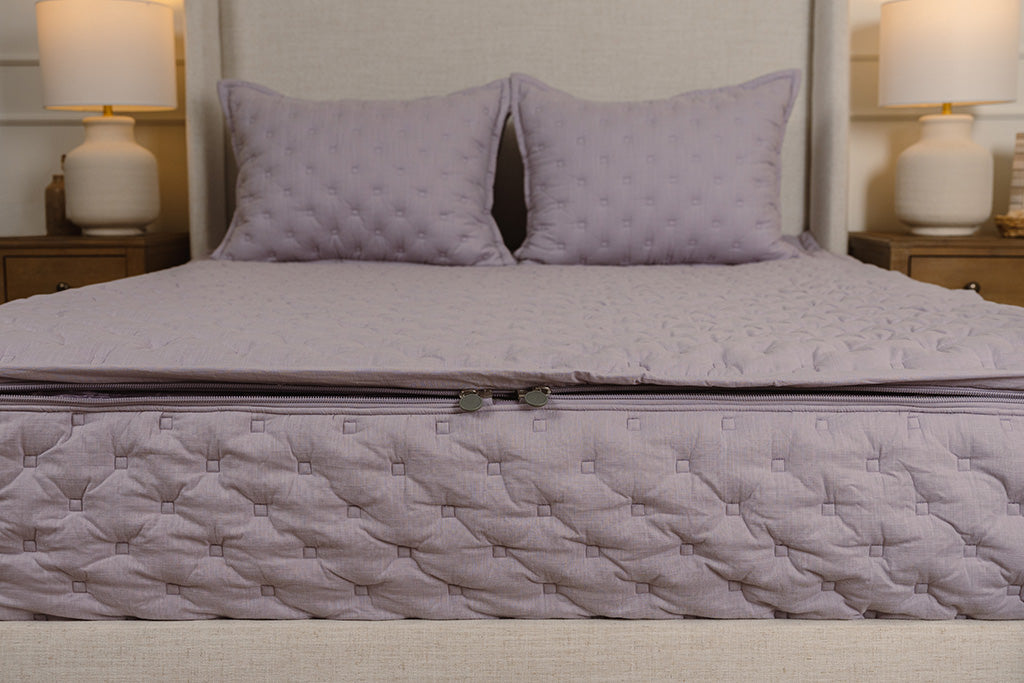 End of bed showing double zippers on purple puffed zipper bedding.