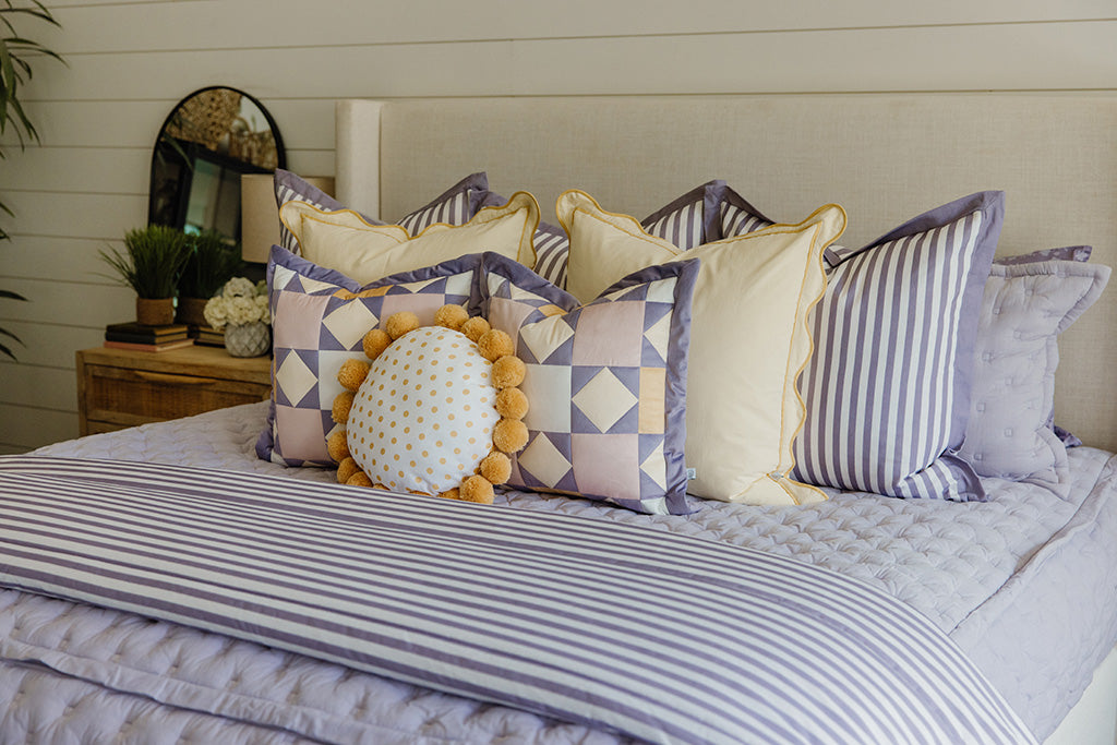 A purple puffed bedding with yellow, purple, and cream accessories. 