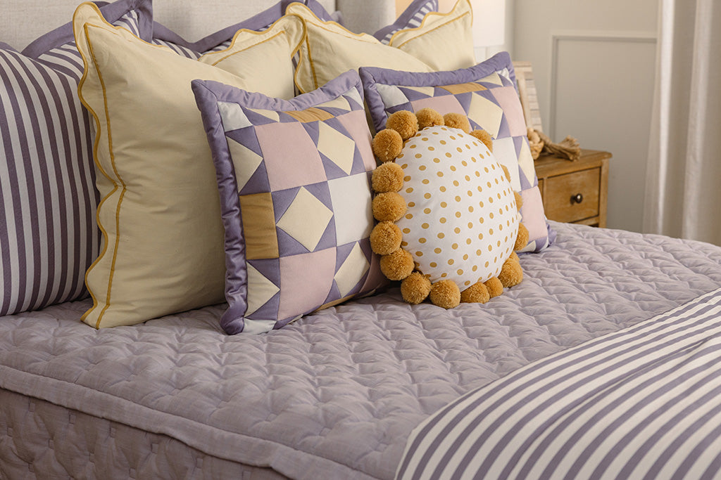 A purple knitted bed with purple, yellow, and white accessories. 